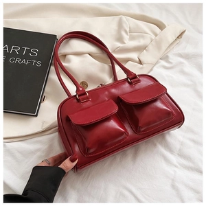 Detail of red glossy leather handbag with vintage double front pockets and bronze hardware