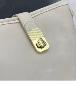 Detailed close-up of cream suede bucket bag featuring a gold twist-lock metal clasp