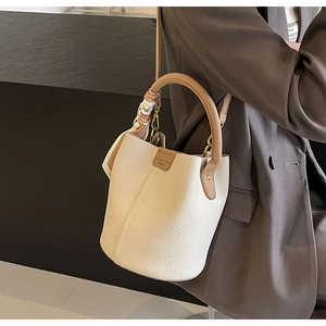 Close-up of cream pebble leather bucket bag with brown handles and silk scarf detail