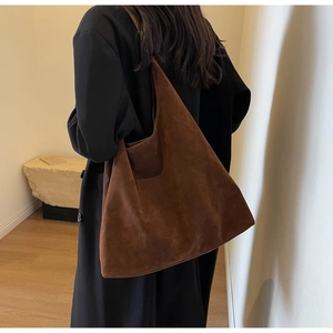 Deep brown oversized matte suede tote bag worn over a classic black winter coat