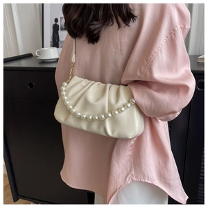 Close-up of pleated cloud bag in cream white with decorative pearl chain strap