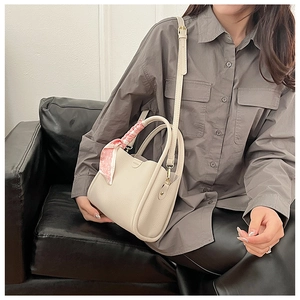 Détail du sac à main en cuir beige avec foulard en soie à motif cœur sur la poignée