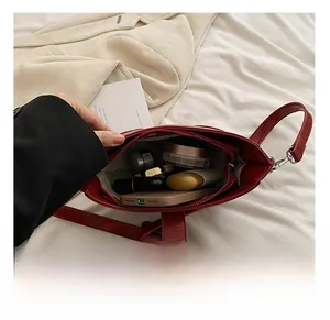 Vue intérieure montrant la capacité du sac bandoulière rouge avec maquillage