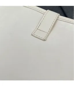 Close-up of white leather bucket bag with precise stitching and stylish lock buckle