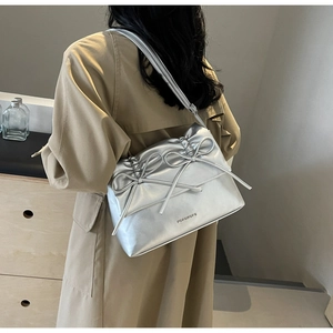 Detail of silver metallic shoulder bag with leather bows and embossed logo