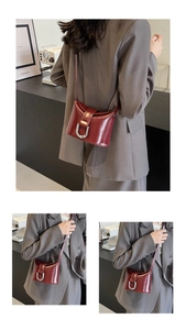 Detail view of burgundy patent leather bucket bag with silver U-shaped metal lock and strap