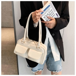 Chic beige shoulder bag with dual front pockets shown in a stylish lifestyle setting