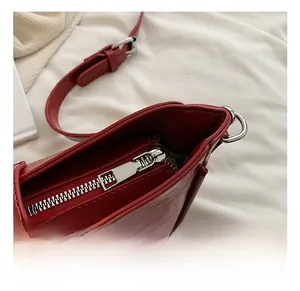 Détail du sac en cuir verni rouge froissé avec fermeture éclair et anneau argenté