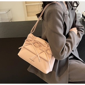 Detail view of pink leather bag featuring double decorative bows and adjustable strap