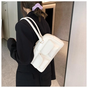 Cream shoulder bag featuring double front flap pockets on a black suit model outfit