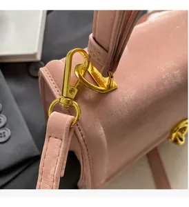 Détail du sac à main rose montrant la boucle en métal doré brillant et la texture