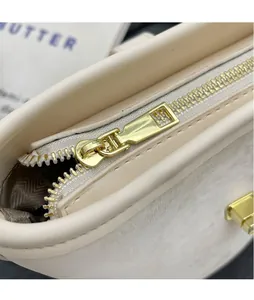 Detailed close-up of premium golden zipper and hardware on beige suede bucket bag