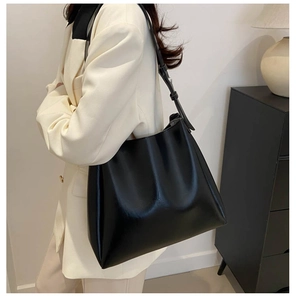 Grand sac cabas en cuir noir classique porté à l'épaule par un mannequin en studio