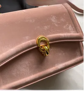 Gros plan sur la boucle dorée du sac en cuir rose à texture vintage raffinée