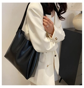 Détail d'un sac cabas en cuir noir porté avec un blazer blanc pour un look chic