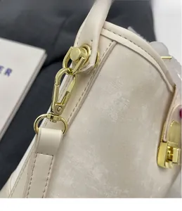 Macro detail of creamy faux leather bucket bag with golden metal hook and lock