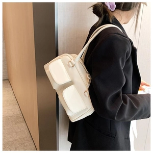 Detail of off-white faux leather handbag with dual front pockets and metal zipper closure