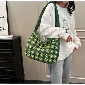 Detail of green quilted cloud bag featuring 3D crochet floral embellishments and soft texture