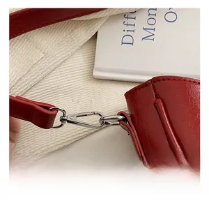 Détail d'un sac à main en cuir verni rouge avec un crochet de fermeture en métal argenté