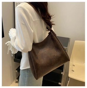 Sac fourre-tout vintage en simili cuir marron porté à l'épaule par un mannequin élégant