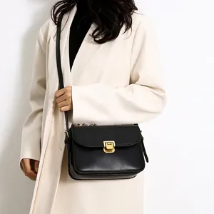 Minimalist black leather crossbody square bag with elegant gold hardware lock and strap