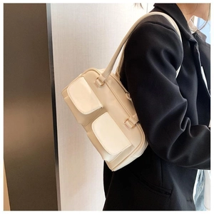 Detailed view of cream PU leather crossbody bag with multiple pockets worn over shoulder
