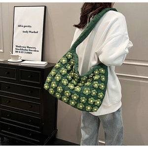 Close-up of dark green quilted tote bag with unique 3D yellow and green floral accents