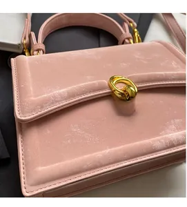 Détail du petit sac carré rose en velours avec boucle en métal doré et texture douce
