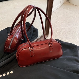 Large burgundy leather Boston bag with silver zippers and thin double straps on dark suit
