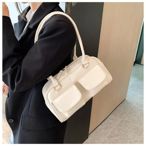 White faux leather shoulder bag with dual front flap pockets worn by a model in a black blazer
