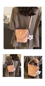 Detailed view of pink suede bucket bag featuring golden twist lock and star plush charm