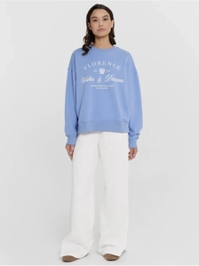 Detail of light blue vintage sweatshirt featuring white college-style lettering and emblem