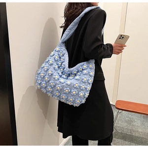 Detail shot of light blue quilted cloud bag with 3D white flower patterns on the surface