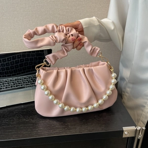Pink pleated cloud bag with pearl chain and scrunched handle in a modern setting