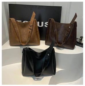 Trois sacs cabas minimalistes en cuir mat marron et noir sur un présentoir étagé