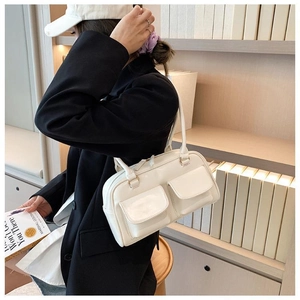Close-up of off-white faux leather handbag featuring two front flap pockets and slim handles