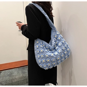 Detail of light blue quilted cloud bag featuring 3D blue and yellow knitted flower accents