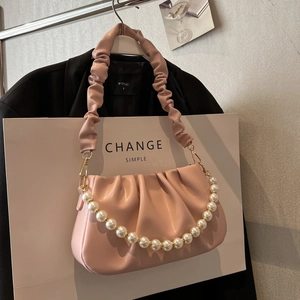 Pink ruched cloud bag with large faux pearl strap and golden hardware on display
