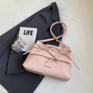Pink PU leather crossbody bag with bow decoration on a minimalist white background