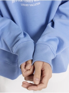 Detail of light blue sweatshirt featuring ribbed cuffs and vintage white letter printing