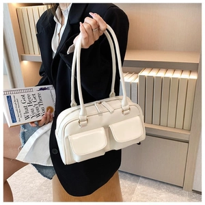 Detail view of cream white minimalist handbag with dual front pockets and thin straps
