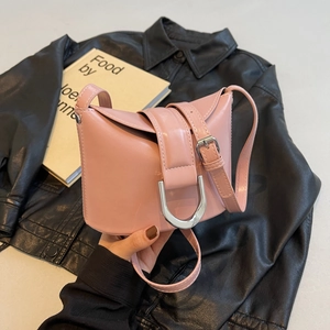 Pink glossy leather bucket bag with oversized silver metal buckle on black background
