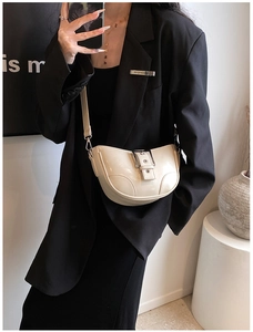 Sac bandoulière demi-lune blanc crème en cuir verni brillant porté par un mannequin