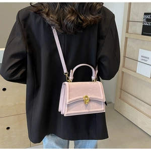 Détail du sac bandoulière en cuir lavande avec fermoir tournant doré et poignée élégante
