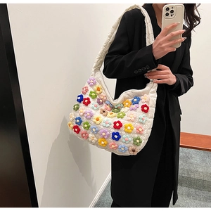 Detail of white quilted cloud bag with colorful knit flower appliques on shoulder strap