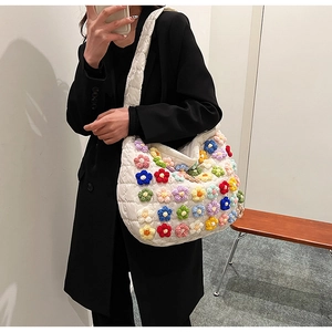 Detail of white quilted puffer tote bag with colorful 3D crochet flower decorations