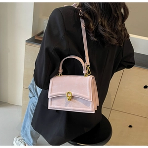 Détail du sac bandoulière en daim rose avec boucle dorée et design latéral en accordéon