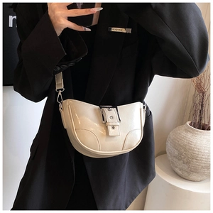 Detail of cream white high-gloss saddle bag with metal buckle on a black suit model