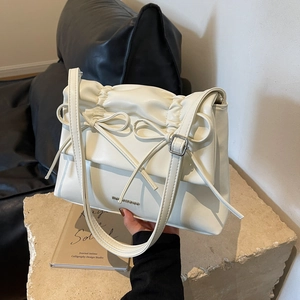 Chic cream-colored shoulder bag with ribbon details on textured stone base