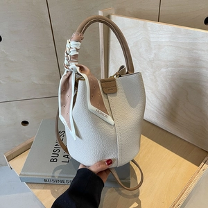 White litchi pattern leather bucket bag with brown handles and a decorative scarf